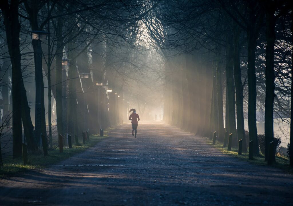 woman running in through trees during sunset